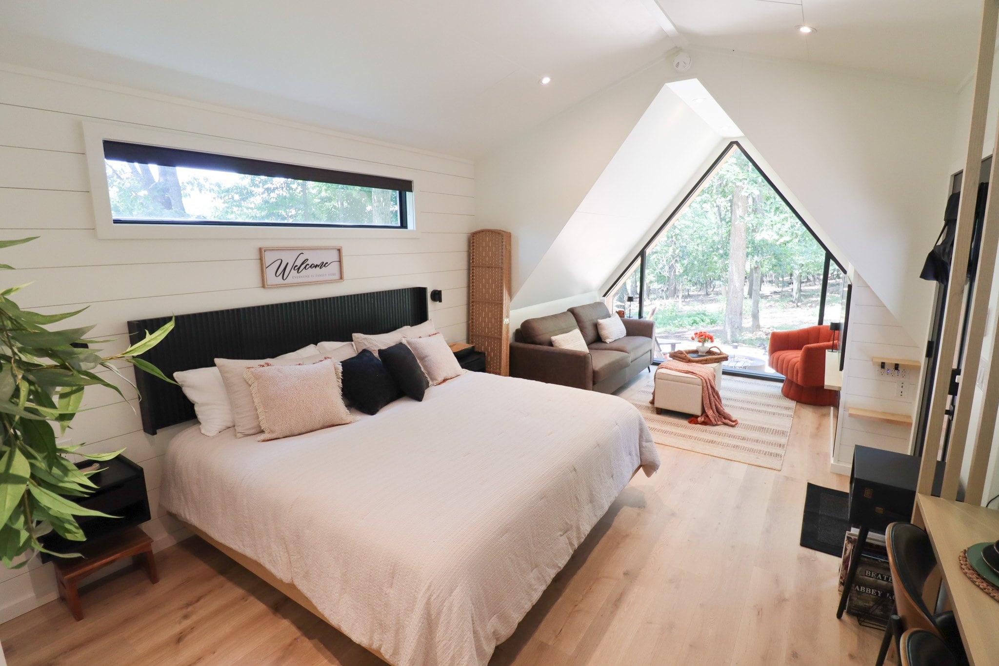 The bedroom under the sloped A-frame ceiling, beside the gable window