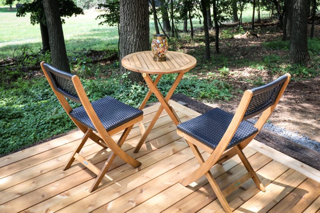 A bistro table and chairs on the deck among the trees