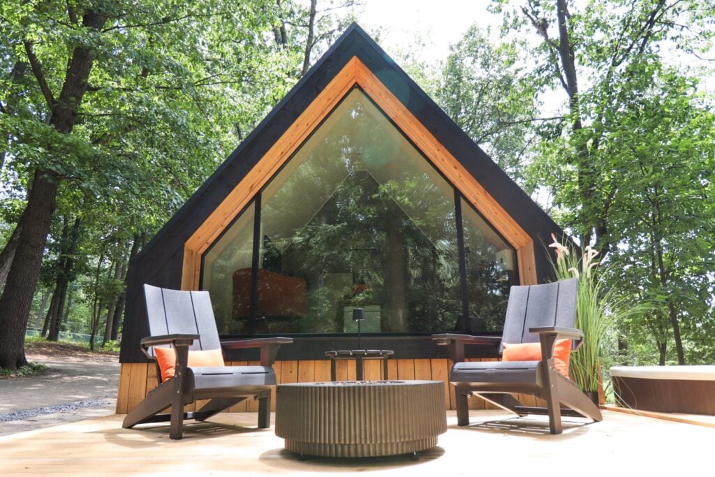 The A-frame cabin in daylight with Adirondack chairs on the deck