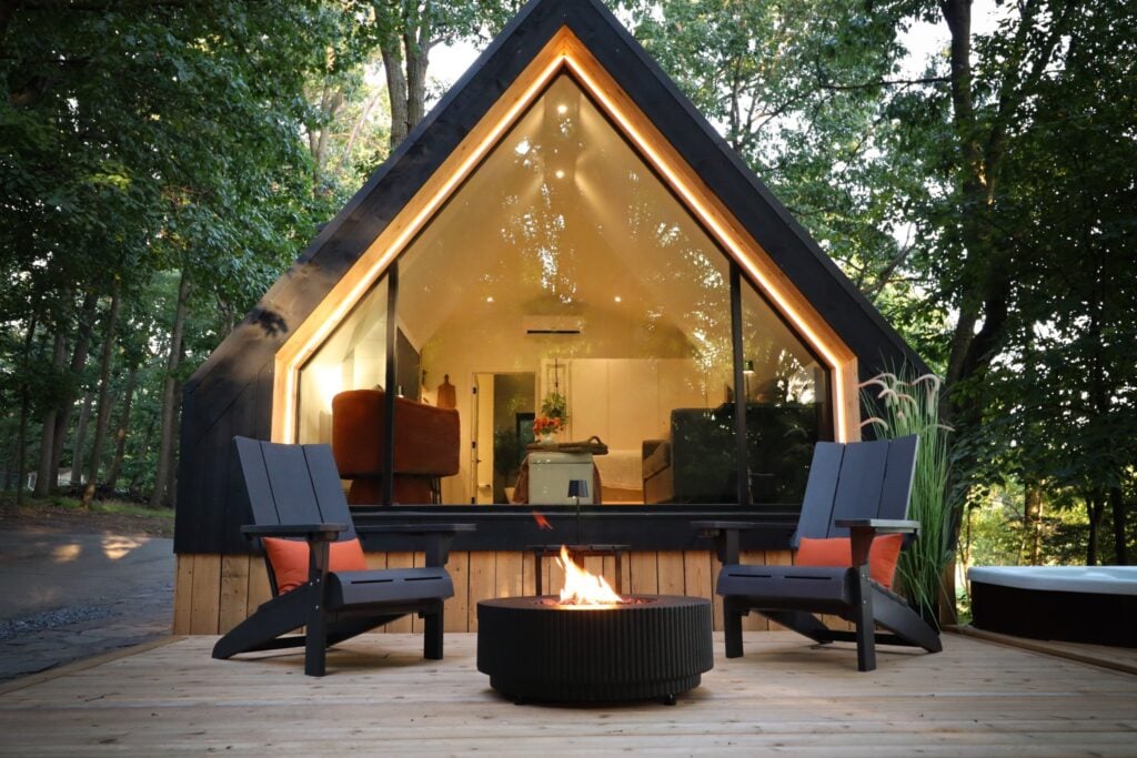 The A-frame cabin at dusk seen across its wooden deck