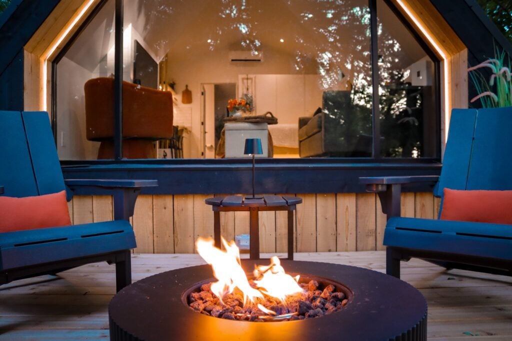 The fire pit lit in the evening, chairs arranged around it